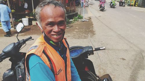 Portrait of happy man riding motorcycle on road