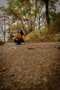 Full length of man sitting on road in forest