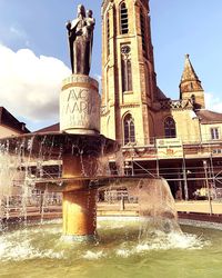 Water fountain in building against sky