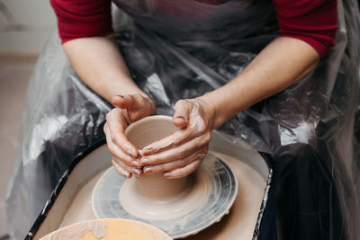 Close up of woman hands molding clay mug spinning on pottery wheel. potter hands forming clay cup