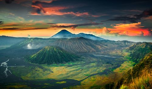 Scenic view of mountains against cloudy sky during sunset