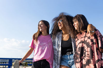 Three beautiful young women of different races with their long board boards and smiling