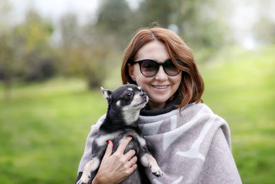 Portrait of young woman with dog on field