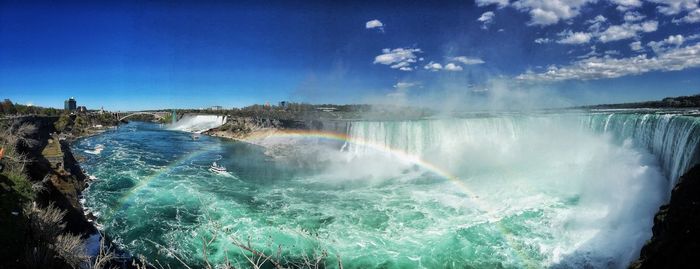 Panoramic view of waterfall against blue sky