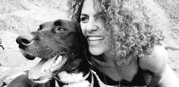 Close-up of cheerful young woman with dog at beach