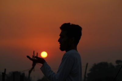 Silhouette man standing against orange sky during sunset