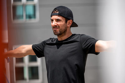 Young man looking away while exercising against wall