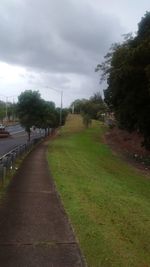 Road passing through landscape against cloudy sky