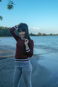 Full length portrait of young woman standing on beach
