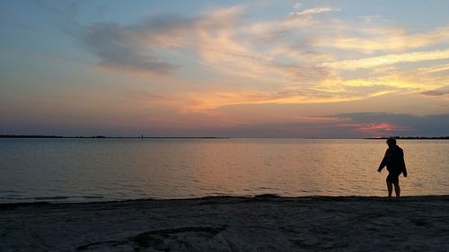 People standing on beach at sunset