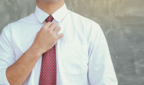 Midsection of man wearing hat standing against wall