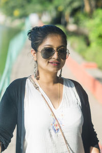 Portrait of young woman wearing sunglasses standing outdoors