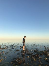 Man standing on beach against clear sky