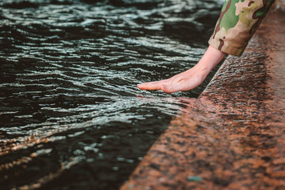 The girl's wet hand is stroking the wave. touching the river with the palm of your hand
