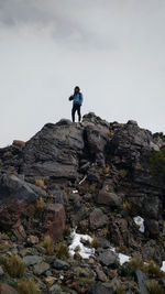 Low angle view of man standing on rocky mountain