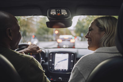 Happy mature couple talking to each other while traveling in car