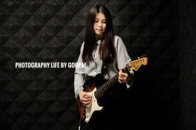 Portrait of young woman playing guitar