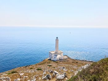 Lighthouse by sea against clear sky