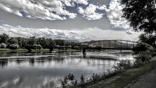 Bridge over river against cloudy sky