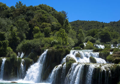 Scenic view of waterfall in forest against sky