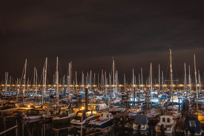 Sailboats moored at harbor against sky at night