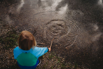 Back view of child playing with water rings at the lake in a park