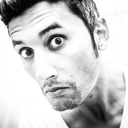 Close-up portrait of young man with raised eyebrows against white background