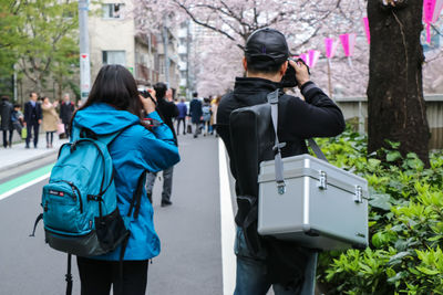 Rear view of man and woman standing by tree