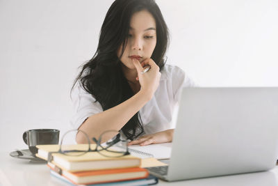 Young woman using phone while sitting on table