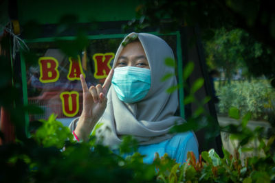 Portrait of a woman wearing a mask near a plant