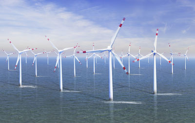 Traditional windmill in sea against sky