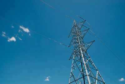Low angle view of electricity pylon against blue sky