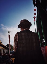 Rear view of man standing against sky in city