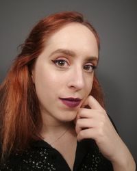 Portrait of beautiful young woman against gray background