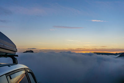 Airplane flying over sea against sky during sunset