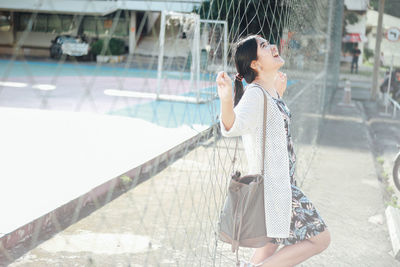 Young woman leaning on net in court