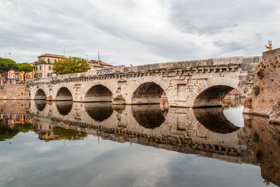 Arch bridge over river against sky