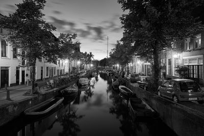 Boats moored on canal in city against sky