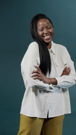 Portrait of young woman standing against blue background