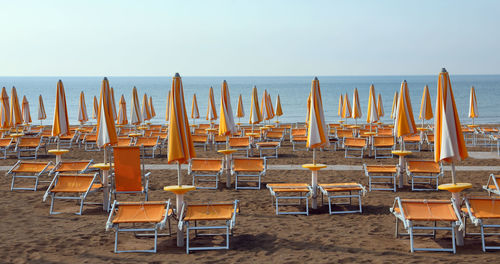 Empty chairs on beach against clear sky