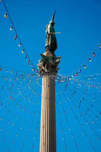 Low angle view of lighting decoration on architectural column against blue sky