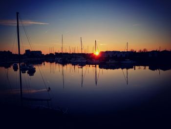 Boats moored in water at sunset