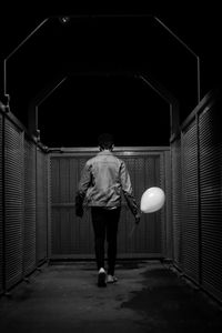 Rear view full length of young man holding balloon at night