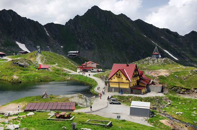 High angle view of houses by lake and mountains against sky