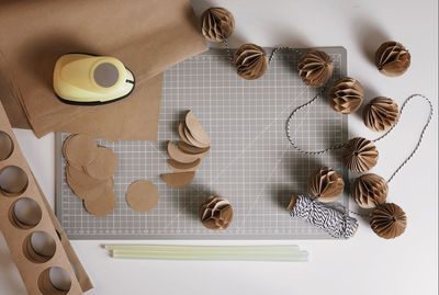 Top view of craft christmas paper decorationmaking of festive garland with diy honeycomb paper balls