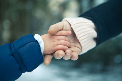 Cropped image of mother and child holding hands