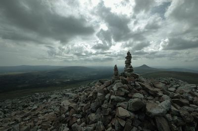 Stack of rock on landscape against cloudy sky