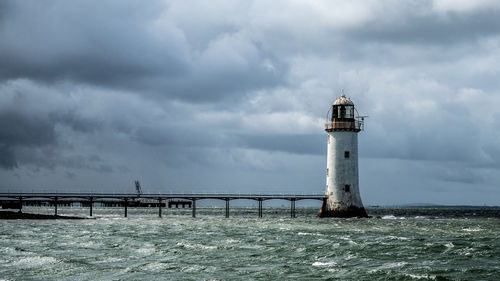 Lighthouse in sea against sky