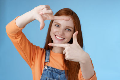 Portrait of a smiling young woman drinking against blue background