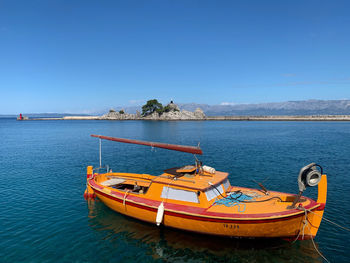 Boat moored in sea against clear blue sky